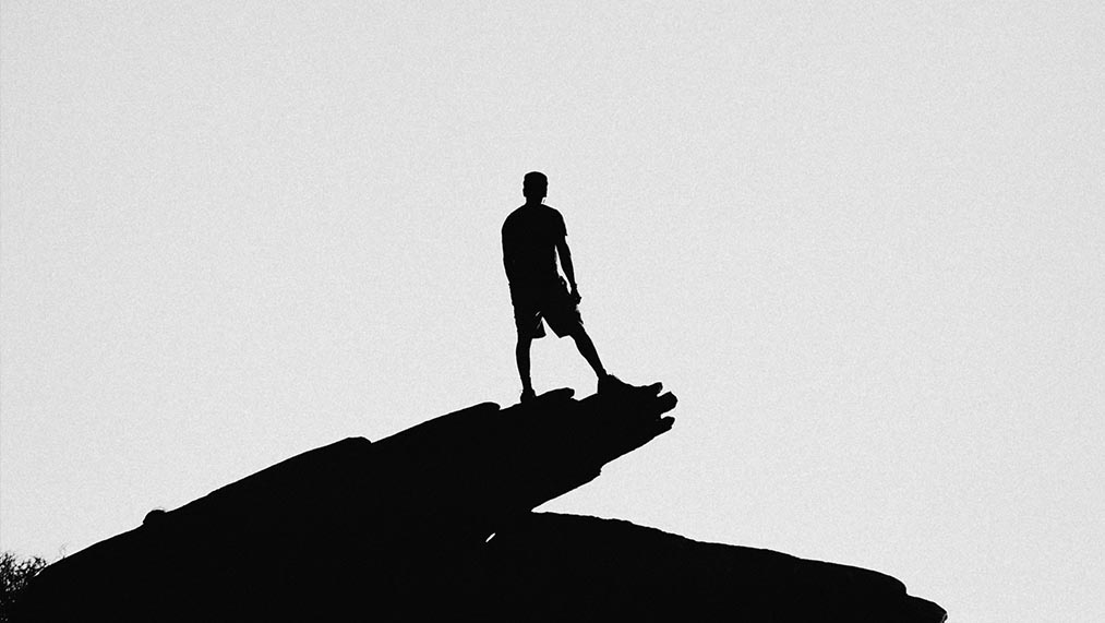 silhouette of man on a cliff