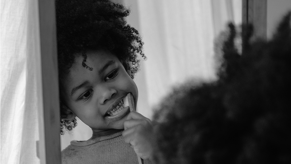 a child brushing their teeth with a bamboo toothbrush